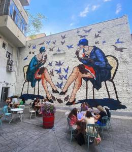 een muurschildering van mensen die in stoelen voor een muur zitten bij City Side Up Exclusive in Belgrado