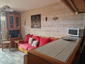 TrévigninにあるTERRES D'HISTOIRES Locationsのリビングルーム(赤いソファ、テレビ付)