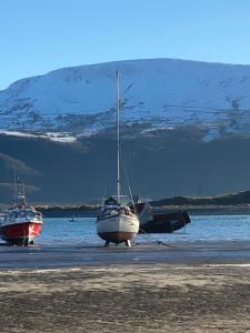 two boats are parked on a beach near the water at Aelfor Cozy Cottage in Barmouth