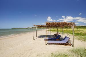 two lounge chairs on a beach next to the water at VILA PITHAYA - Casa Jambo Rosa in Japaratinga