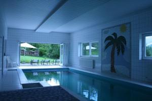 a swimming pool in a house with a palm tree mural at Haus Rottenstein in Neukirchen