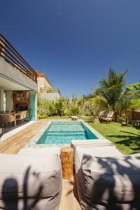 a swimming pool in a backyard with two couches at VILA PITHAYA - Casa Jambo Rosa in Japaratinga
