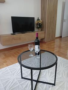 einen Glastisch mit einer Flasche Wein und zwei Gläsern in der Unterkunft Welcome Apartments in Niš
