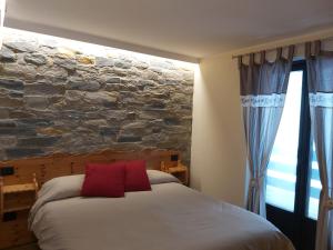a bedroom with a bed with a stone wall at La petite maison in La Thuile