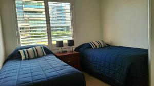 een slaapkamer met 2 blauwe bedden en een raam bij Hibiscus Court 1 Forster Main Beach in Forster