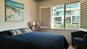 a bedroom with a blue bed and two windows at Hibiscus Court 1 Forster Main Beach in Forster