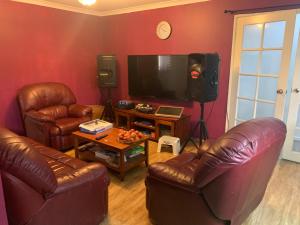 sala de estar con 2 sillas de cuero y TV de pantalla plana en Lovely house in canning vale, en Perth