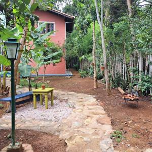 un giardino con una casa, un tavolo e una lampada di Suite Solteiro Cristal Rosa, Suites Ananda a Alto Paraíso de Goiás