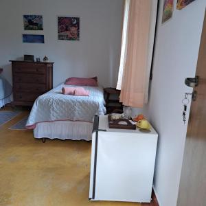 a small bedroom with a bed and a refrigerator at Suite Solteiro Cristal Rosa, Suites Ananda in Alto Paraíso de Goiás