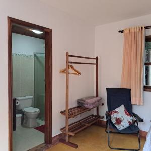 a bathroom with a shower and a toilet and a chair at Suite Solteiro Cristal Rosa, Suites Ananda in Alto Paraíso de Goiás