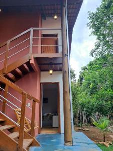 a house with a staircase leading up to a balcony at Suite Solteiro Cristal Rosa, Suites Ananda in Alto Paraíso de Goiás