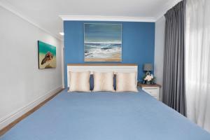 a blue bedroom with a large bed with pillows at BJ Mick's Lakefront Apartment in Forster