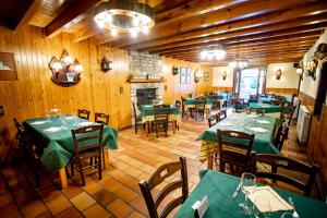 un restaurante con mesas verdes, sillas y chimenea en Camping Valle de Bujaruelo, en Torla