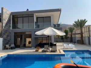 a house with a swimming pool and an umbrella at Follow Sea Villa in Sowayma