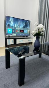 szklany stół z telewizorem i wazon z kwiatami w obiekcie 2 bedrooms new brand with amazing view w mieście Adżman