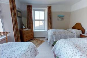 a bedroom with three beds and a window at Afallon Aberdaron in Aberdaron