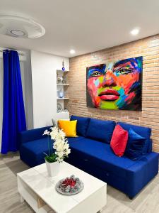 a blue couch in a living room with a painting at Rambla Apartment by the Sea in Alicante