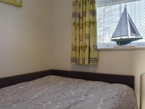 a bedroom with a bed and a window with a model of a boat at Beach Walk in Kessingland