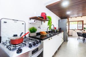 uma cozinha com fogão e panela em Casa Charmosa com Piscina em Barra do Una em Barra do Una