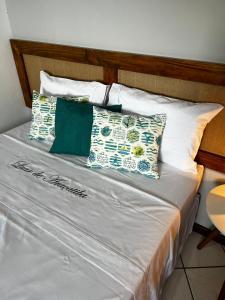 a bed with white and green pillows on it at Luar de Araçatiba Suítes in Praia de Araçatiba
