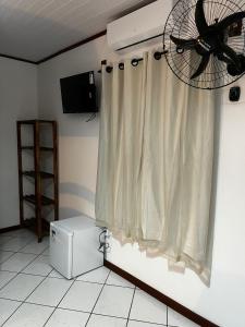 um quarto com uma ventoinha de tecto e uma cortina em Luar de Araçatiba Suítes em Praia de Araçatiba