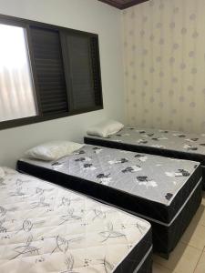 two beds sitting in a room with a window at Casa em Caldas - PISCINA SOLAR E ELETRICA in Caldas Novas