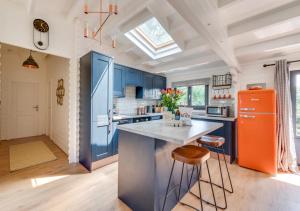 - une cuisine avec des armoires bleues et un réfrigérateur orange dans l'établissement Woodpecker Lodge, à Stradbroke