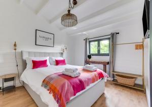 - une chambre avec un grand lit blanc et des oreillers roses dans l'établissement Woodpecker Lodge, à Stradbroke