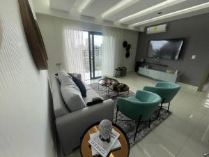 a living room with a couch and chairs and a tv at Soha Panorama B13 King Bed High Floor Balcony View in Santiago de los Caballeros