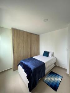 ein Schlafzimmer mit einem großen Bett mit einer blauen Decke in der Unterkunft Cartagena 3 habitaciones 9 personas cerca a la playa Wifi y Parqueadero in Cartagena de Indias