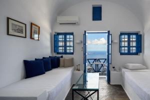 a living room with two couches and a glass table at Heliotopos in Imerovigli