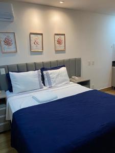 een slaapkamer met een groot bed met blauwe lakens en kussens bij Flat no Transamerica Hotel in Campos dos Goytacazes