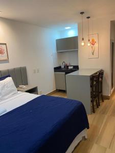 a bedroom with a blue bed and a kitchen at Flat no Transamerica Hotel in Campos dos Goytacazes