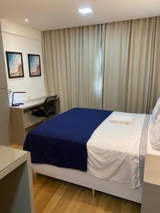 um quarto com uma cama grande, uma secretária e um computador em Flat no Transamerica Hotel em Campos dos Goytacazes