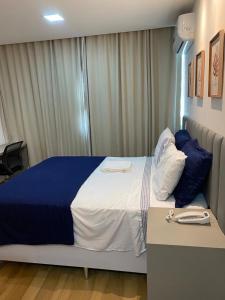 Schlafzimmer mit einem großen Bett mit blauer und weißer Bettwäsche in der Unterkunft Flat no Transamerica Hotel in Campos dos Goytacazes