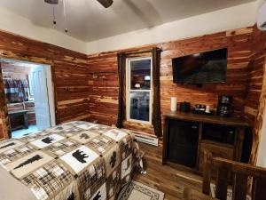 um quarto com uma cama e uma televisão de ecrã plano em Log Cabin Inn em Eureka Springs