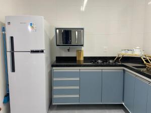 a kitchen with blue cabinets and a white refrigerator at Kitão Canto do Forte in Praia Grande