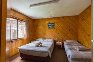 two beds in a room with wooden walls at Wonboyn Cabins in Wonboyn