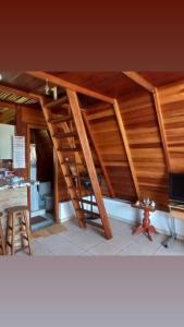 uma escada de madeira num quarto com uma cozinha em Cantinho da Vandisa em Ilhabela