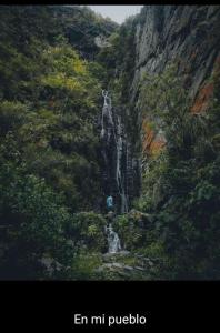 a person is standing in front of a waterfall at La Bendición in Campo Quijano