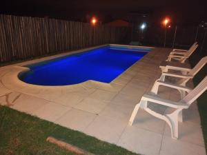 a swimming pool with two chairs next to it at night at La Bendición in Campo Quijano