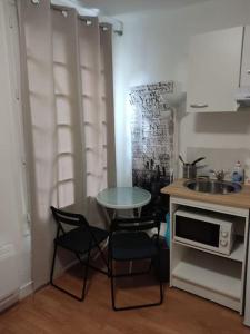 a kitchen with a table and chairs and a sink at Studio Paris 13 in Paris