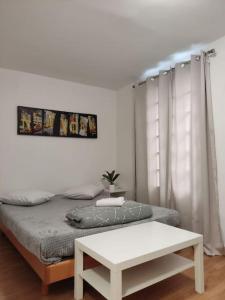 a white bedroom with a bed and a table at Studio Paris 13 in Paris