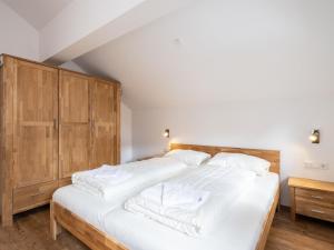 - une chambre avec un grand lit blanc et des placards en bois dans l'établissement Kobelhäusl bei Hause XL, à Neukirchen am Großvenediger