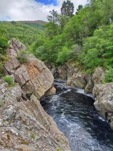 a river with rocks and trees on a mountain at Riverside Lodge in Killiecrankie in Bridge of Tilt