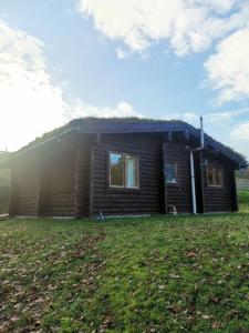 a small house with a grass yard in front of it at Riverside Lodge in Killiecrankie in Bridge of Tilt