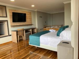 Hotel Entre Brumas في Aguadas: غرفة نوم بسرير كبير وتلفزيون