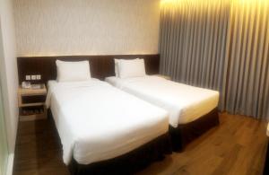 two beds in a hotel room with white sheets at Harmoni Hotel Garut in Garut