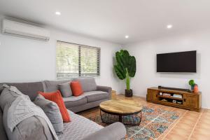 a living room with a couch and a flat screen tv at 13 Orania Court in Rainbow Beach