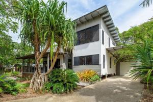a white house with a palm tree in front of it at Naiad 12 in Rainbow Beach
